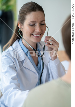 Smiling female young doctor in a lab coat with a stethoscope 135296227