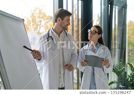 Female doctor making presentation to her colleague sand both looking involved Female doctor making presentation to her colleague sand both looking involved 135296247