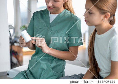 Pediatric nurse explaining medication instructions to young girl 135296335