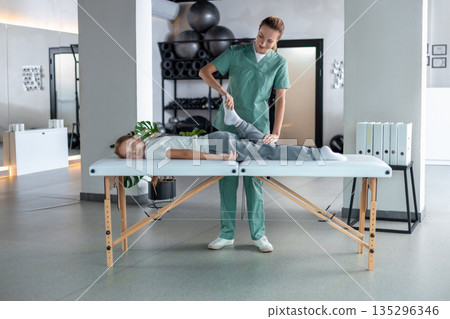 Woman therapist performing little girl leg stretching lying on couch 135296346