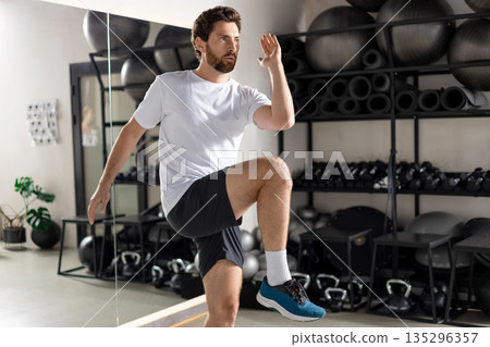 Bearded young man exercising in the gym and looking focused Bearded young man exercising in the gym and looking focused 135296357