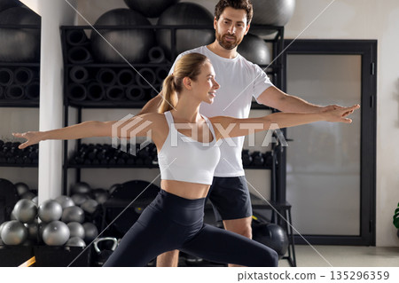 Blonde woman working with a coach in the gym and looking concentrated Blonde woman working with a coach in the gym and looking concentrated 135296359