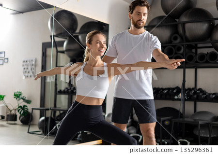 Blonde woman working with a coach in the gym and looking concentrated 135296361