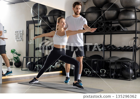 Blonde woman working with a coach in the gym and looking concentrated Blonde woman working with a coach in the gym and looking concentrated 135296362