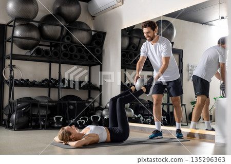 Blonde woman working with a coach in the gym and looking concentrated Blonde woman working with a coach in the gym and looking concentrated 135296363
