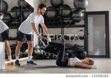 Blonde woman working with a coach in the gym and looking concentrated Blonde woman working with a coach in the gym and looking concentrated 135296364