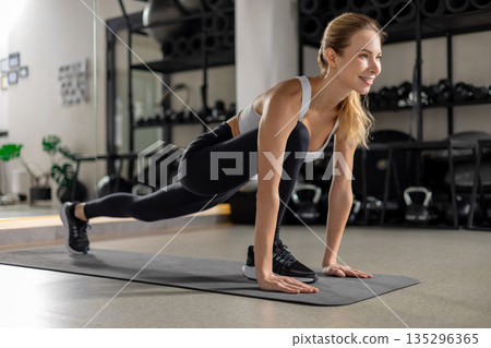 Blonde young woman exercising in the gym and looking determined Blonde young woman exercising in the gym and looking determined 135296365