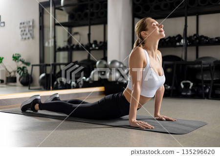 Blonde young woman doing yoga in the gym and looking concentrated 135296620