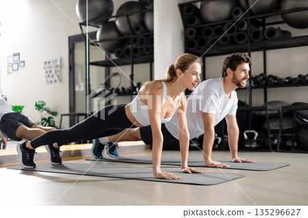 Man and woman exercising together and looking contented and determined 135296627