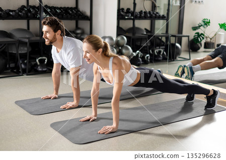 Two people having a workout in gym and standing in plank 135296628