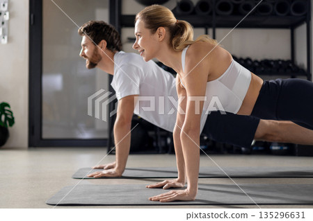 Two people having a workout in gym and standing in plank 135296631