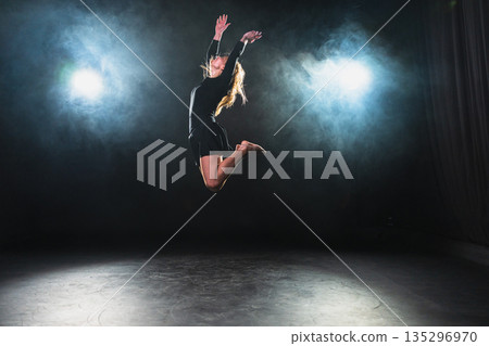Contemporary woman dancer posing on black background with smoke. Adult female artist performer dancing with expression. Modern ballerina dancing in darkness. Passion dance in dark. Flexibility balance 135296970