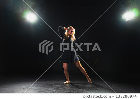 Contemporary woman dancer posing on black background with smoke. Adult female artist performer dancing with expression. Modern ballerina dancing in darkness. Passion dance in dark. Flexibility balance 135296974