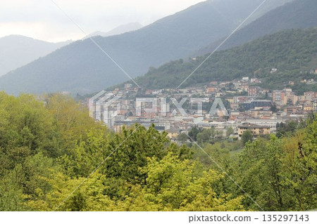 Panoramic view of Lumezzane, a famous industrial hub in Val Trompia, Brescia province, Italy. Houses and factories built on the steep mountain slopes of the Italian Prealps under a cloudy sky 135297143