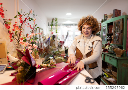 Florist skillfully wraps vibrant bouquet with care in cheerful shop 135297962