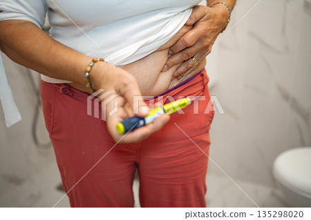 Woman preparing for insulin injection in bathroom setting at home Woman preparing for insulin injection in bathroom setting at home 135298020