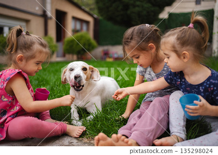Joyful moments with a playful dog and children in a sunny garden Joyful moments with a playful dog and children in a sunny garden 135298024