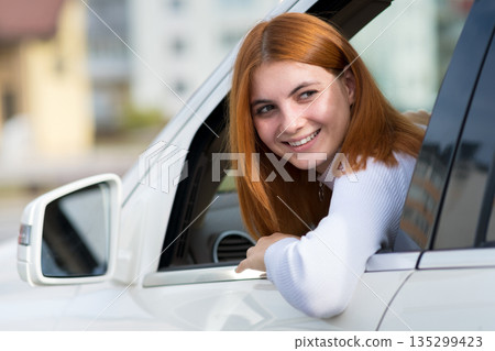 Young woman with red hair driving a car. Young woman with red hair driving a car. 135299423