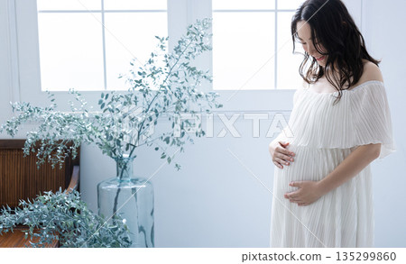 Pregnant woman standing by the window 135299860
