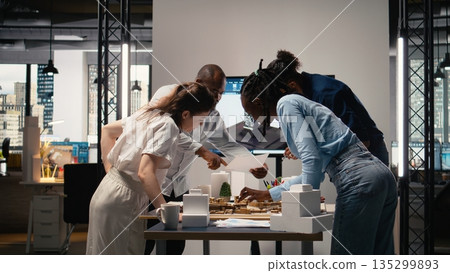 Close up of real estate contractors showing master plan for a housing layout project, using 3D models to present idea of a smart city. Site preparation for urban development vision. 135299893
