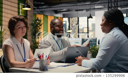 Diverse HR interviewers meeting with an applicant to review CV document, focusing on talent acquisition, work experience and qualifications for onboarding process in enterprise. Camera A. 135299906