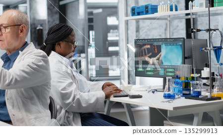 Black woman working in biotechnology lab surrounded by modern equipment. Research study for genetics, nanotechnology and healthcare data, supporting pharmaceutical science. 135299913