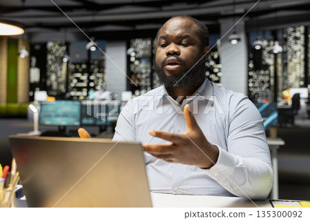 African american man participates in web video call meeting to share insight with associates, speaking confidently about business matters into the microphone. Professional networking. 135300092