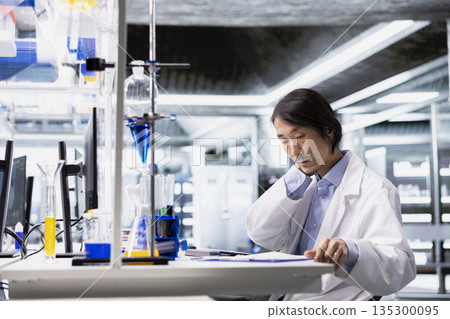 Molecular biologist tired while recording observations from laboratory experiment for research documentation. Fatigued lab worker strained from data logging all day, preparing clinical reports 135300095
