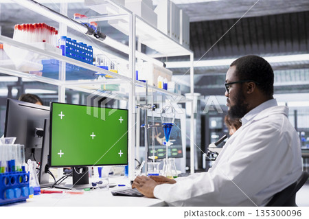 High tech lab expert doing genetics study using clinical equipment, checking analysis results on mockup computer. Man using scientific gear at workbench, doing complex experiments with green screen PC High tech lab expert doing genetics study using clinical equipment, checking analysis results on mockup computer. Man using scientific gear at workbench, doing complex experiments with green screen PC 135300096