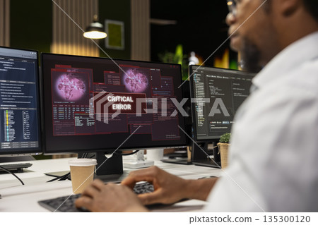 Close up of IT specialist at office desk thinking how to fix critical error alert displayed on PC screen. System administrator brainstorming how to fix computer bug affecting server network 135300120