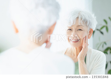 Senior woman feeling the moisture in her skin Senior woman feeling the moisture in her skin 135301848