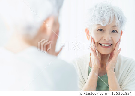 Senior woman feeling the moisture in her skin Senior woman feeling the moisture in her skin 135301854