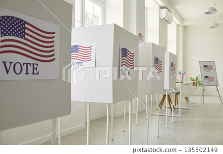 Interior of an empty polling station with a row of white voting booths with American flags 135302149