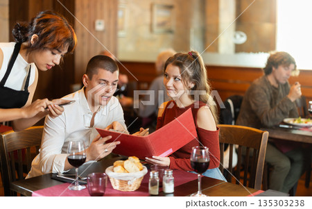 At cafe, Filipino girl waitress communicates with couple of customer, accepts order At cafe, Filipino girl waitress communicates with couple of customer, accepts order 135303238