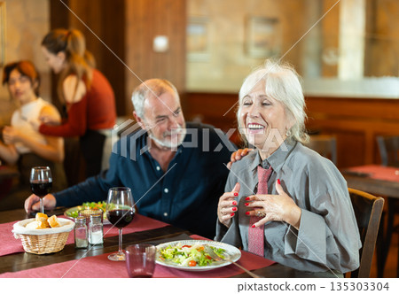 Elderly couple eating and talking in restaurant Elderly couple eating and talking in restaurant 135303304