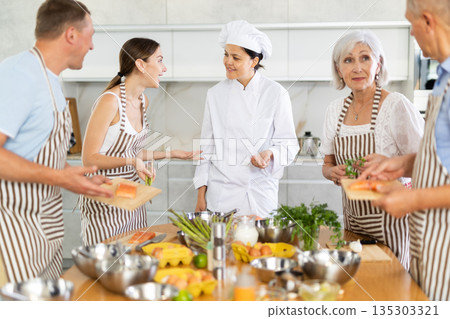Young woman teaching group of people how to cook 135303321