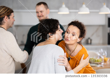 After chatting and gatherings, women friends hug and kiss goodbye. 135303336