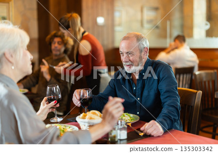 Elderly couple eating and talking in restaurant 135303342
