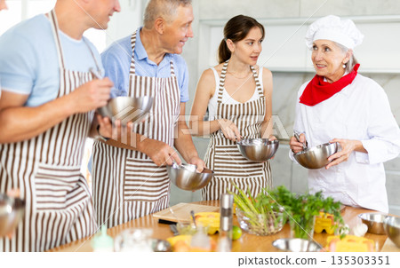 Experienced friendly female chef teaches people how to cook food and how to beat eggs properly in cooking class Experienced friendly female chef teaches people how to cook food and how to beat eggs properly in cooking class 135303351