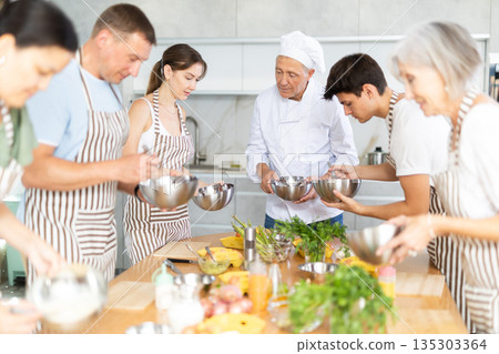 Senior chef sharing professional secrets of cooking at group class 135303364
