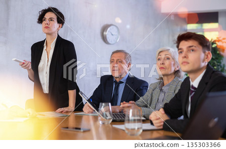 Latin American woman presenting business strategy to partners in office Latin American woman presenting business strategy to partners in office 135303366