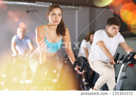 Young girl working out on stationary bicycle in gym 135303372