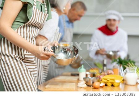 People mixing sauce in bowl with whisk at culinary class 135303382