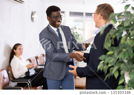 Two adult man shaking hands in reception 135303386