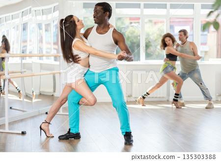 Woman dances incendiary tango with African man partner during choreography lesson Woman dances incendiary tango with African man partner during choreography lesson 135303388
