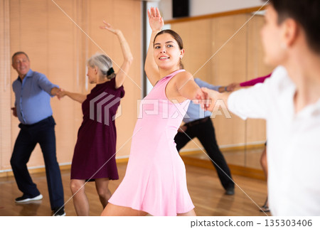 Young girl practicing lindy hop with partner in dance class Young girl practicing lindy hop with partner in dance class 135303406