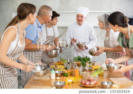Smiling chef sharing secrets of cooking during culinary courses Smiling chef sharing secrets of cooking during culinary courses 135303424