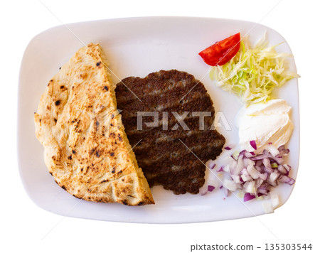 Serbian pljeskavica served with traditional Balkan side dishes on a plate, grilled meat Serbian pljeskavica served with traditional Balkan side dishes on a plate, grilled meat 135303544