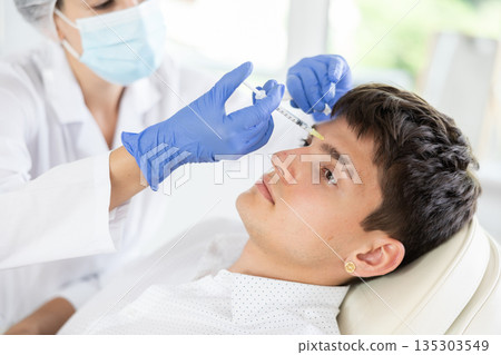 Young man having face care by means of injection in aesthetic clinic 135303549