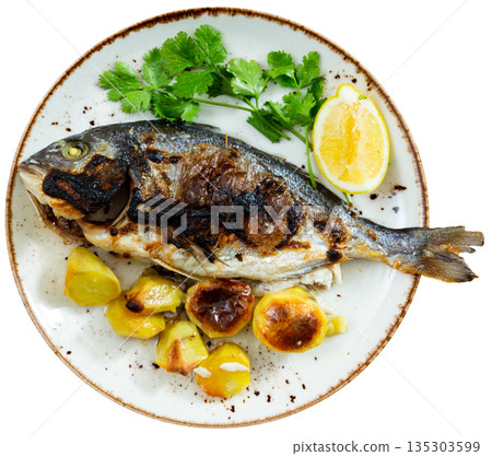 There is large piece of baked fish dorado and potato garnish There is large piece of baked fish dorado and potato garnish 135303599